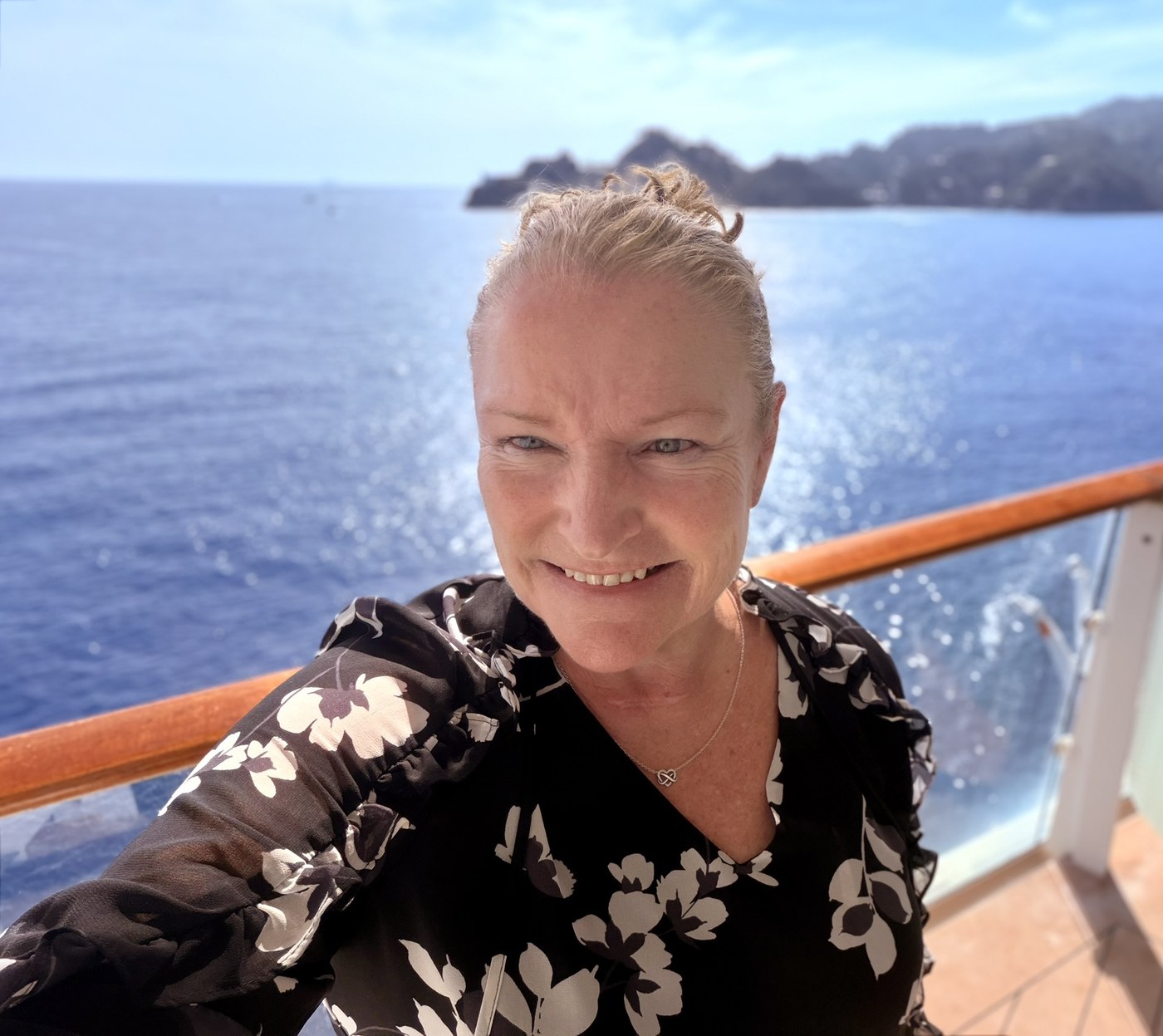 Valerie Scope on a ship balcony overlooking the ocean and a distant coastline